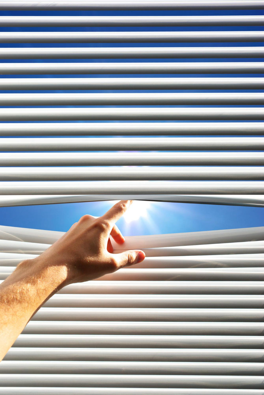 Mano abriendo persiana para dejar pasar la luz del sol