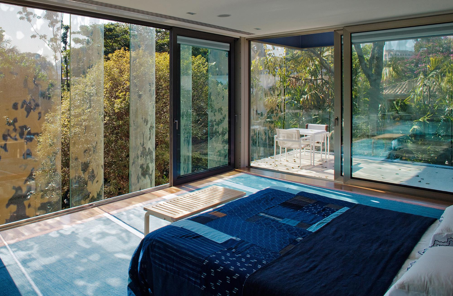 Dormitorio con grandes ventanales de aluminio y vistas al jardín