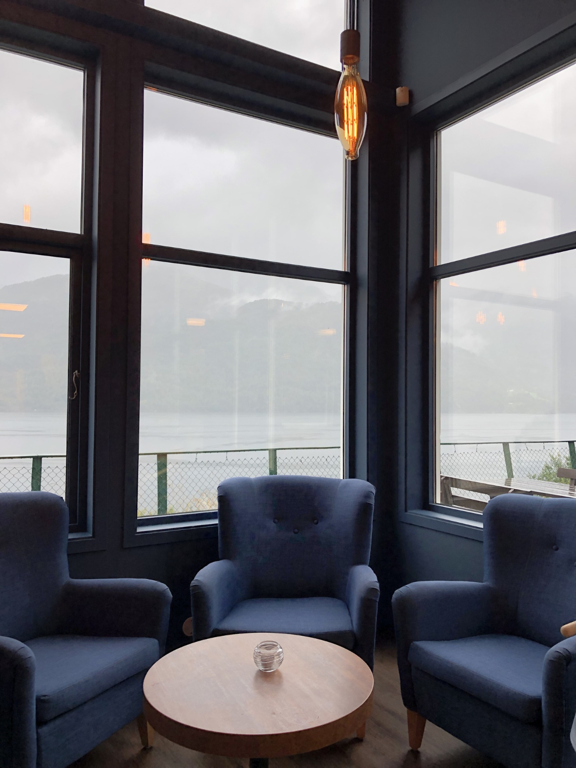 Sala con sillones azules junto a grandes ventanales
